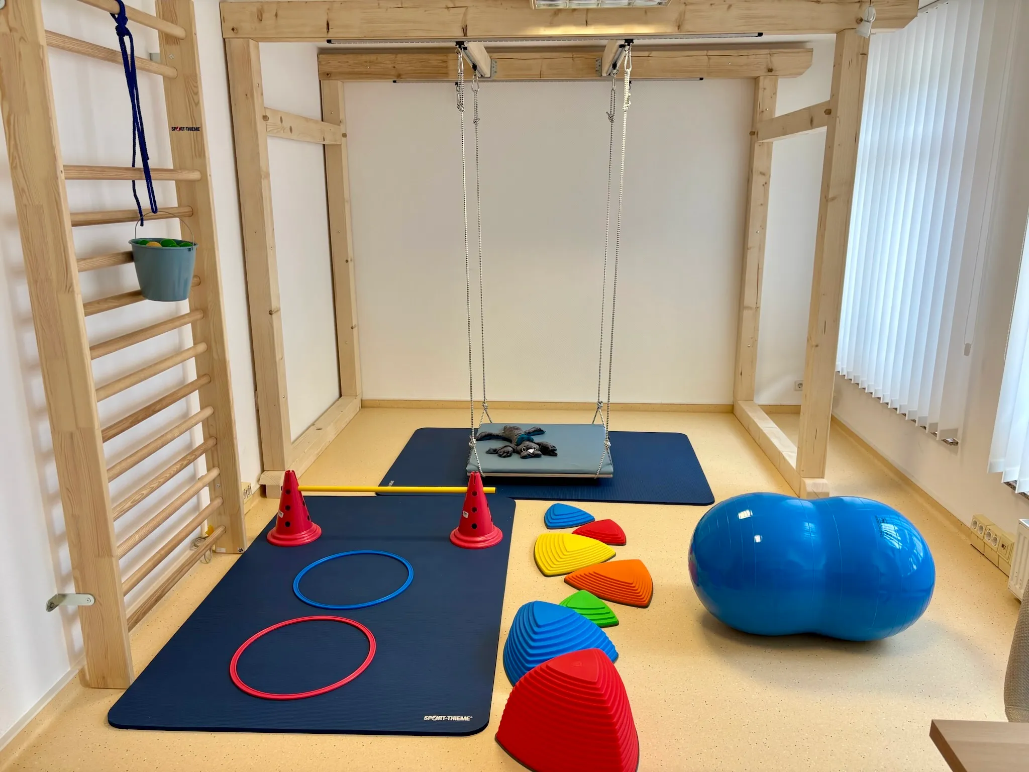 Motorikzentrum mit Deckenschaukel, Sprossenwand, Balanciersteinen und blauer Therapierolle