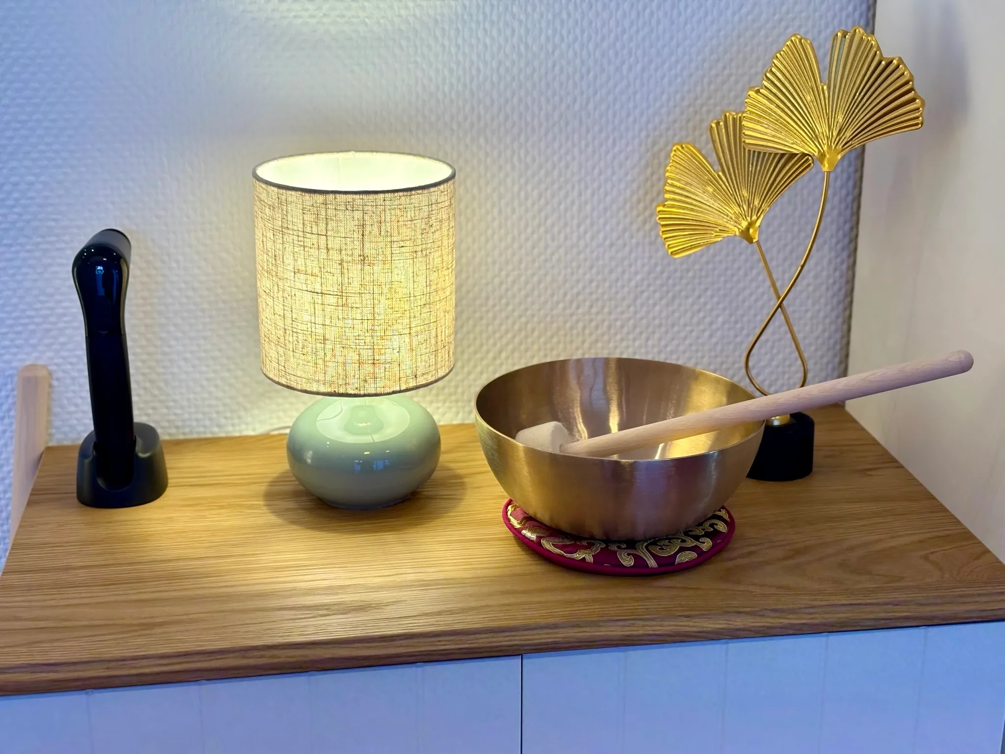 Ablage mit Tischlampe, Klangschale und goldener Ginkgo-Dekoration