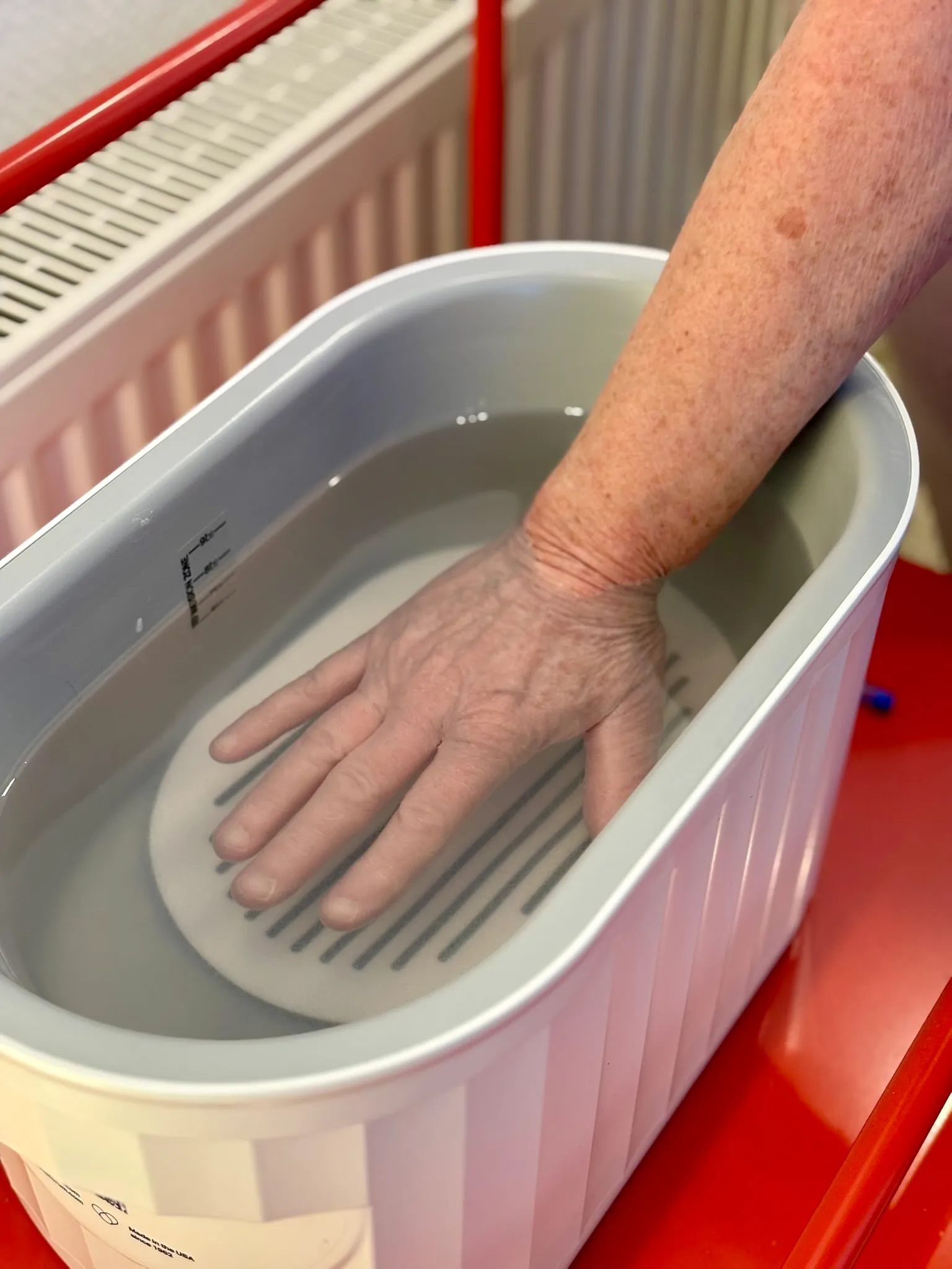 Hand wird in das warme Paraffinbad getaucht